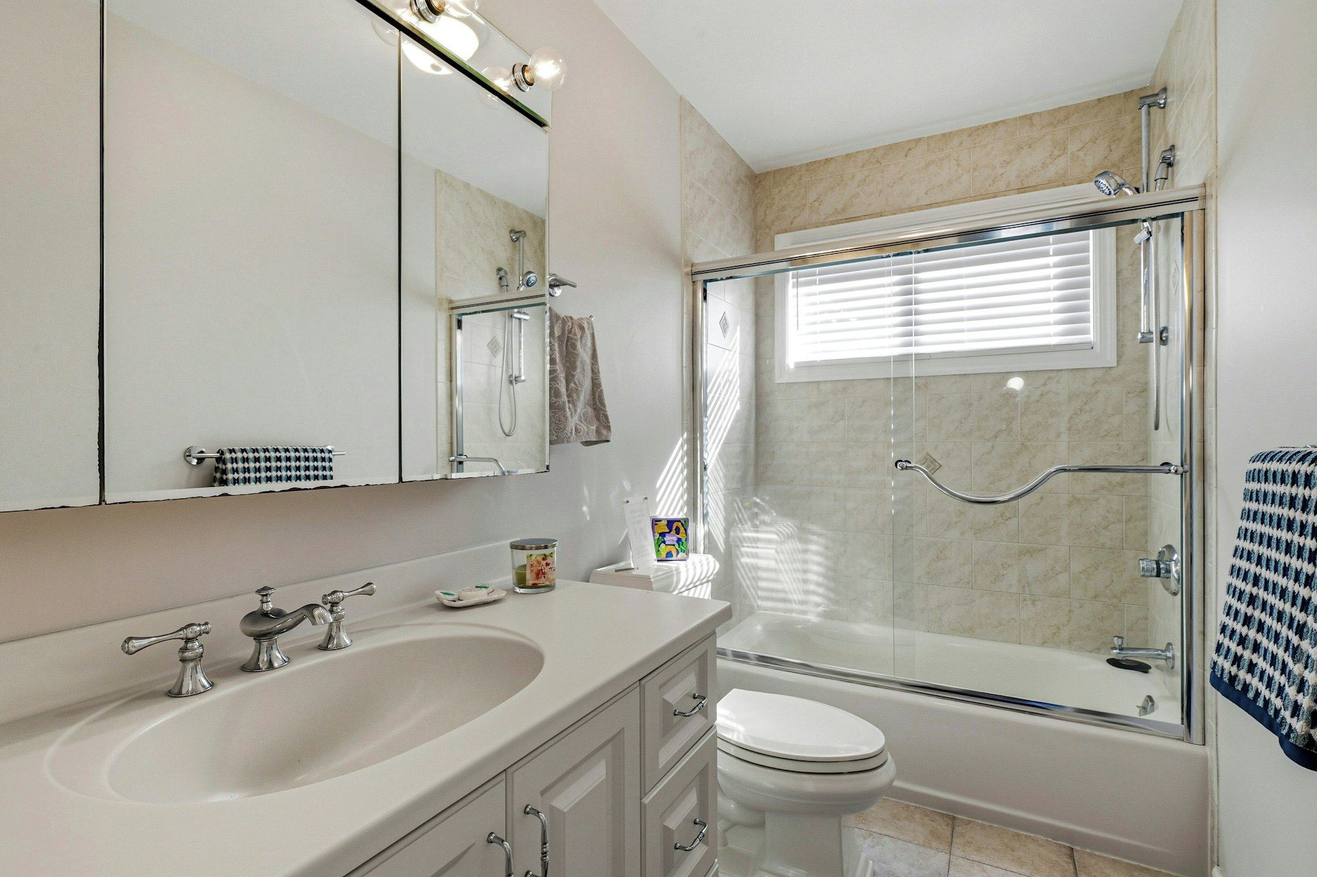 Een badkamer met een groot wastafel, toilet, douche met glazen deur en een spiegel met verlichting.