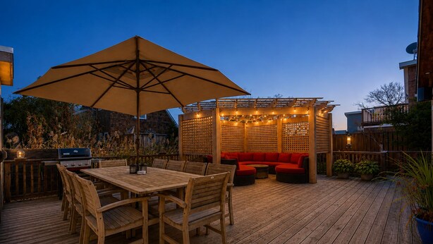 An outdoor patio with a wooden deck, a table with chairs, a red sofa, and string lights. - Pet-Friendly, 5 min walk to beach & ferry (Ocean Beach)