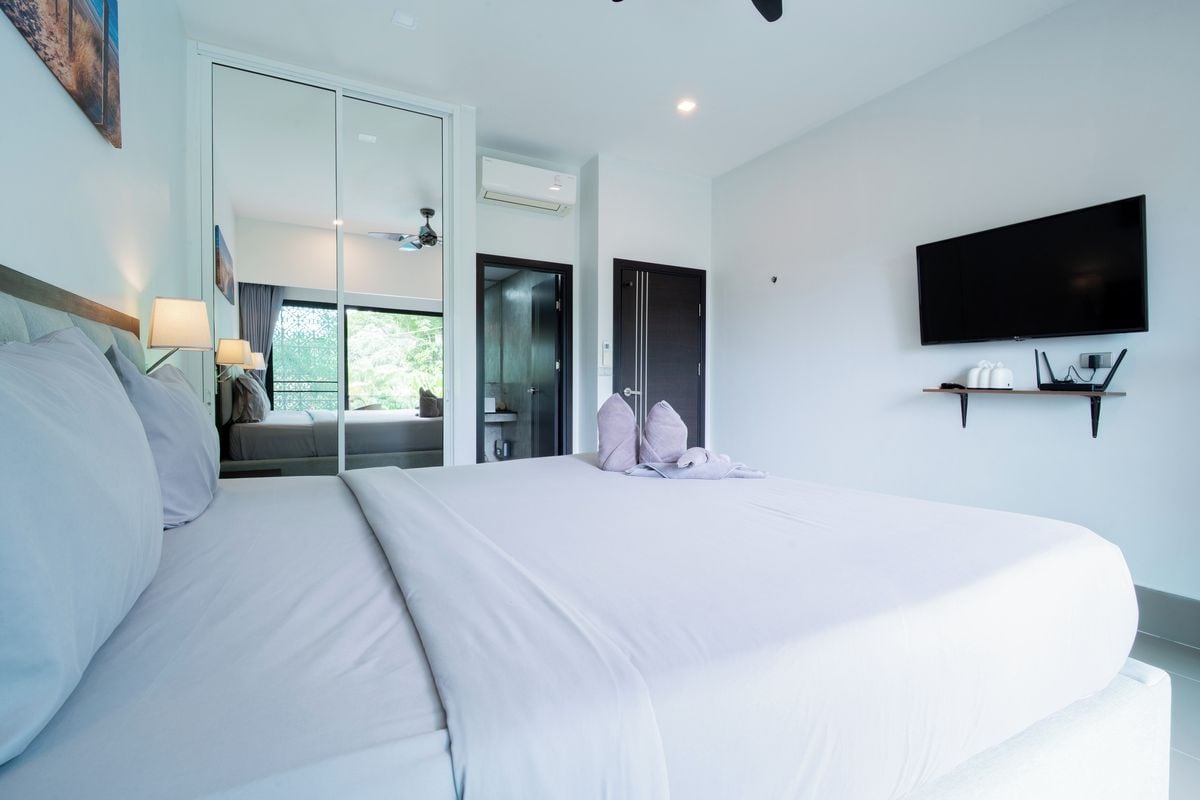 Una camera d'albergo moderna con un letto grande, una televisione a schermo piatto e una porta scorrevole che dà su un balcone.