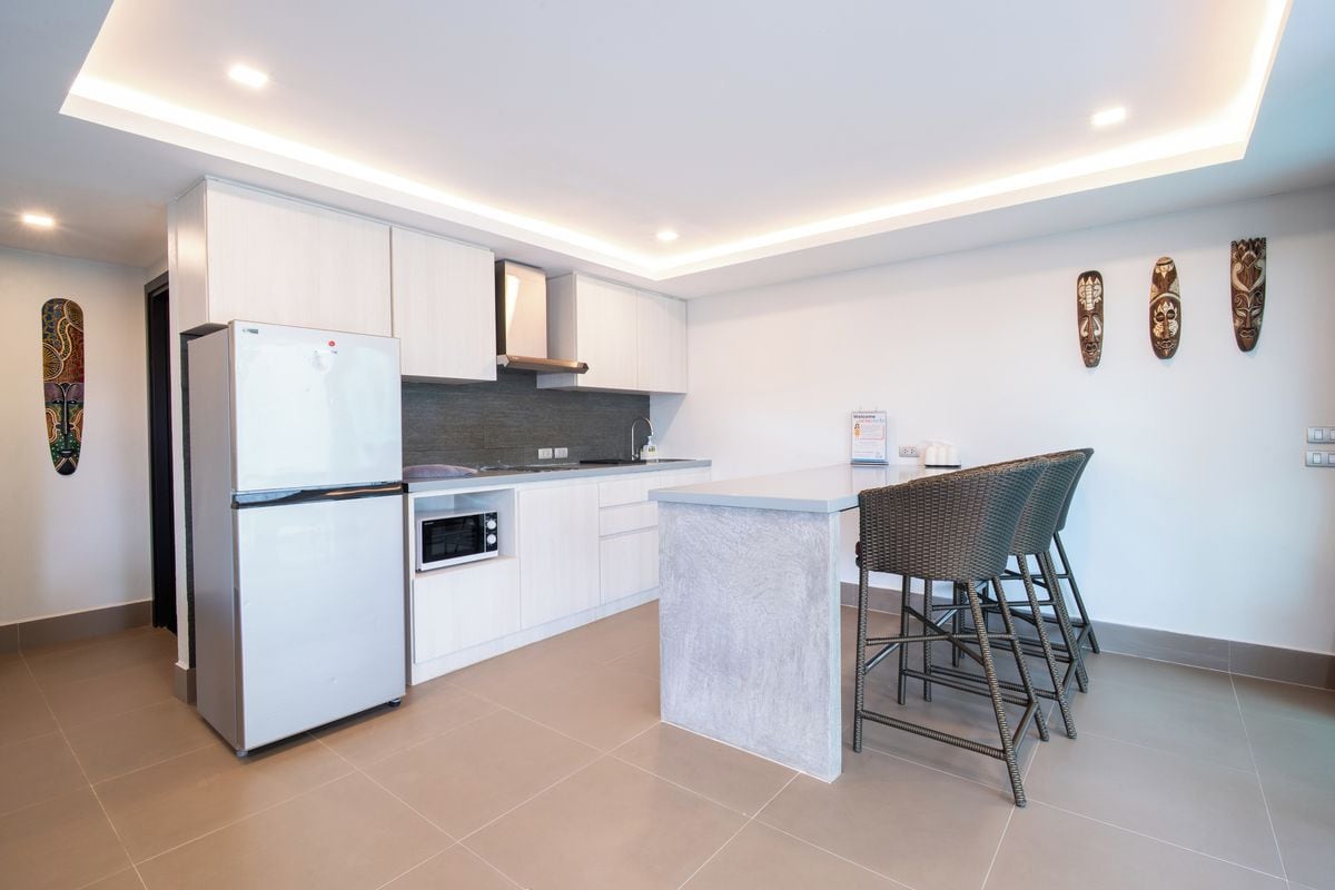 Una cucina moderna con mobili bianchi, forno integrato e un'isola centrale con sgabelli da bar.