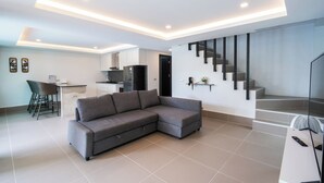 Una sala moderna con un sofá modular, un comedor con una silla y una escalera.