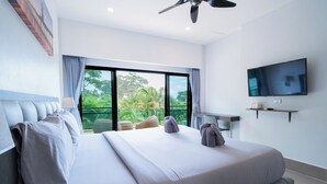 Habitación de hotel con una cama grande, televisor de pantalla plana, ventilador de techo y vistas a zonas verdes.