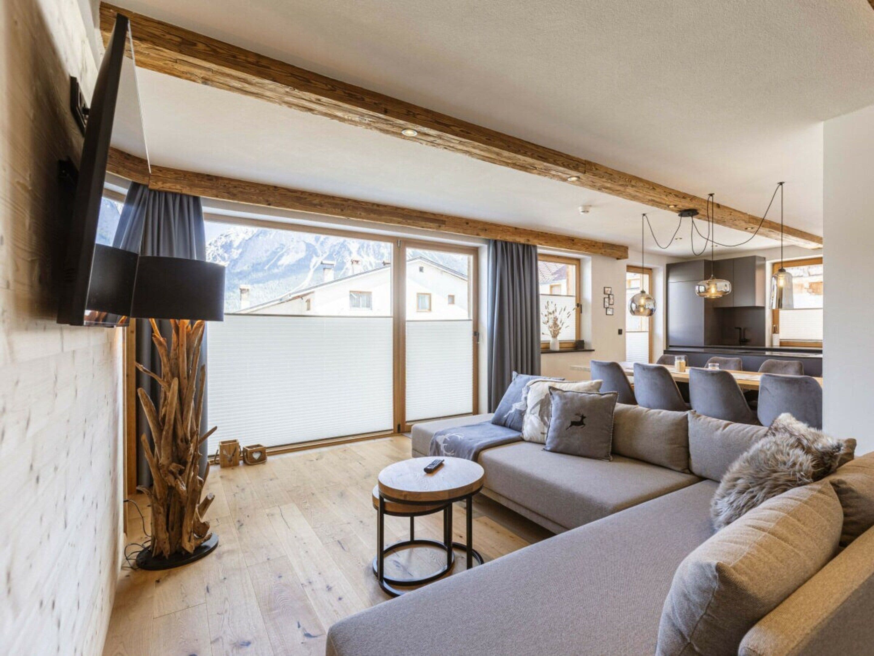 A modern living room with a sofa, a small round table, and a television mounted on the wall.