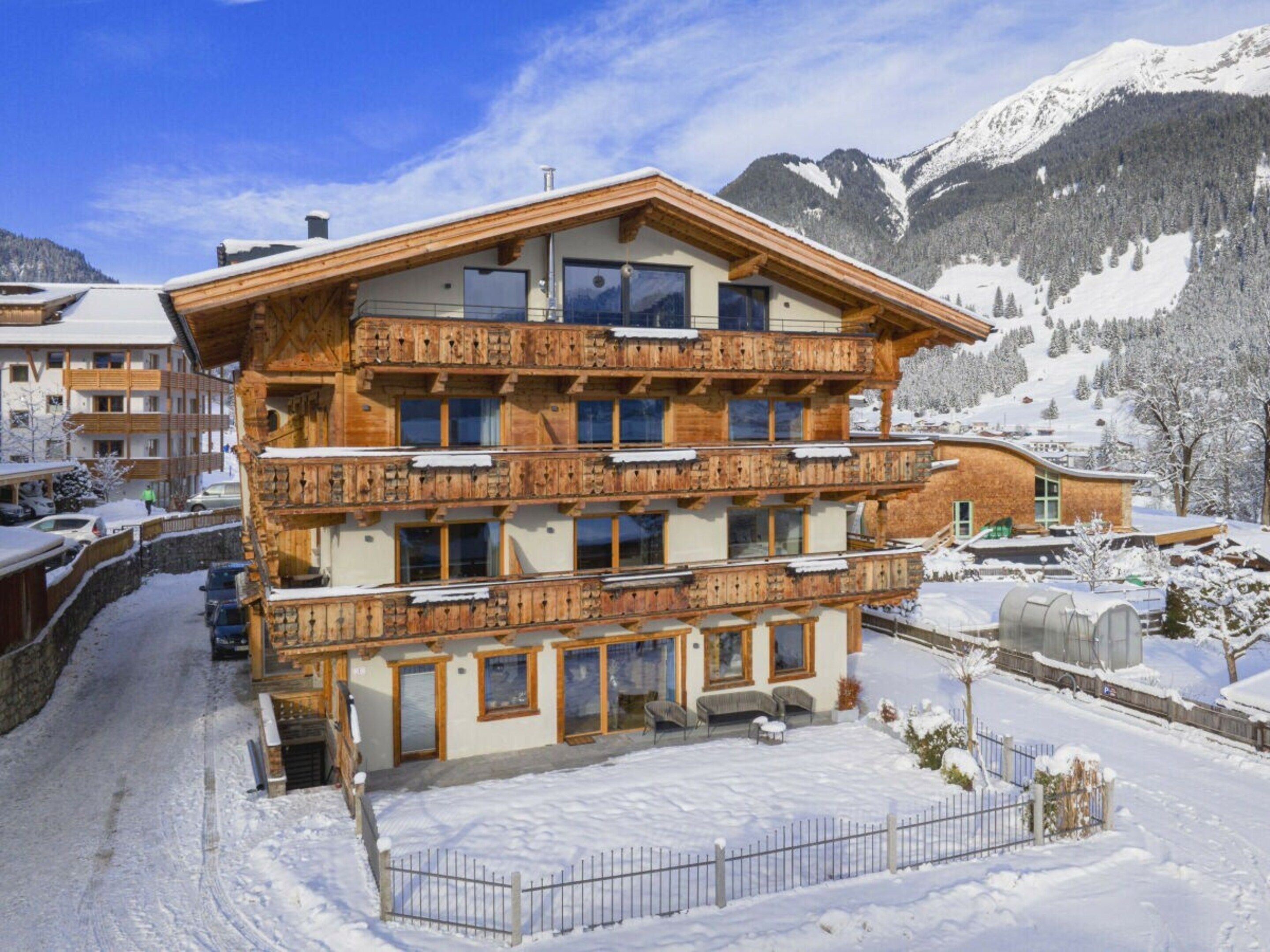 Um edifício de madeira com várias andares e varandas, cercado por montanhas cobertas de neve.