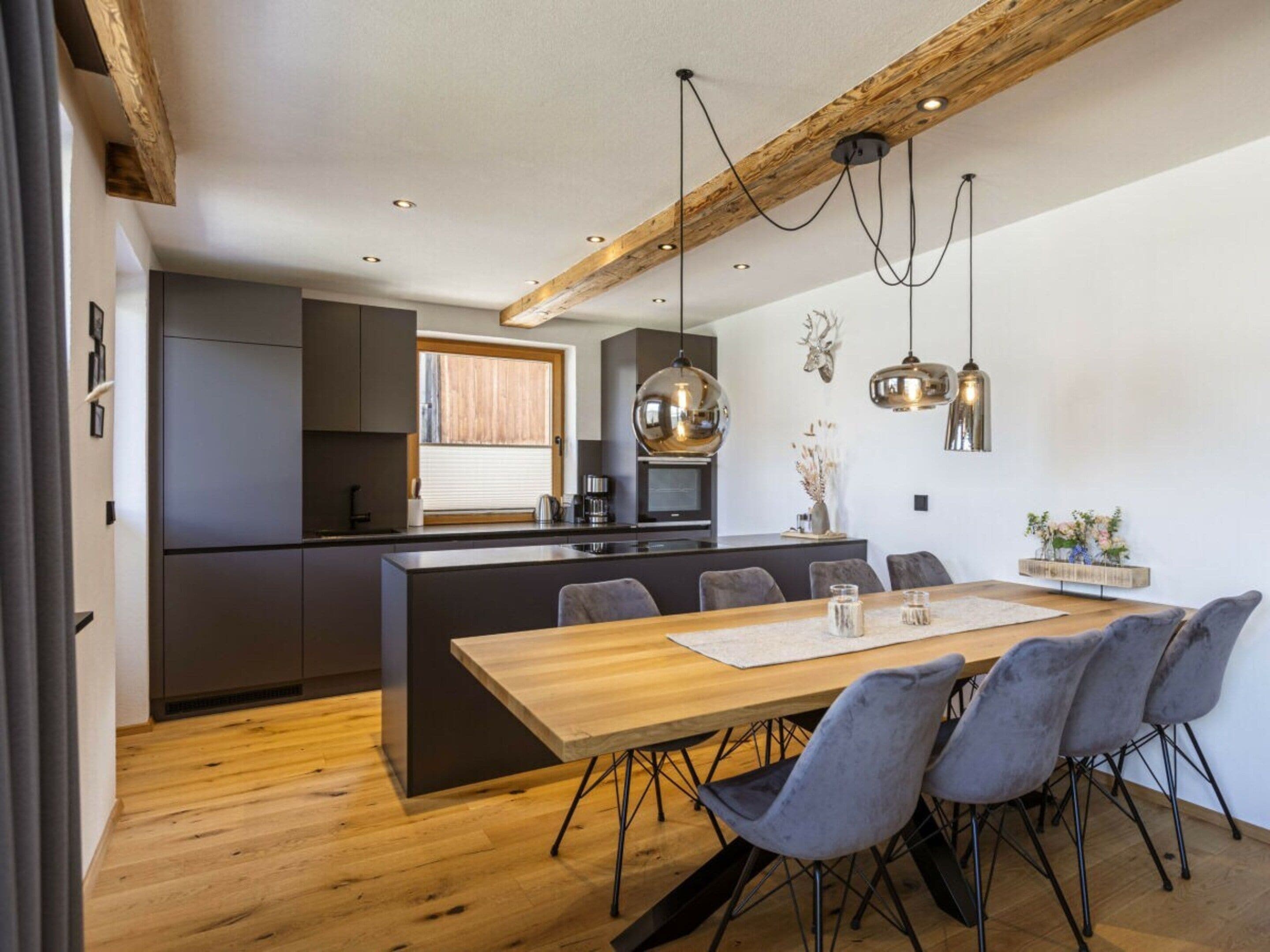 A modern kitchen with a central island, dark cabinetry, and pendant lighting.