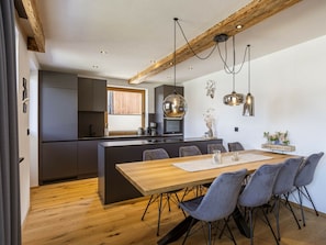 Cocina moderna con una isla central, muebles oscuros e iluminación colgante.