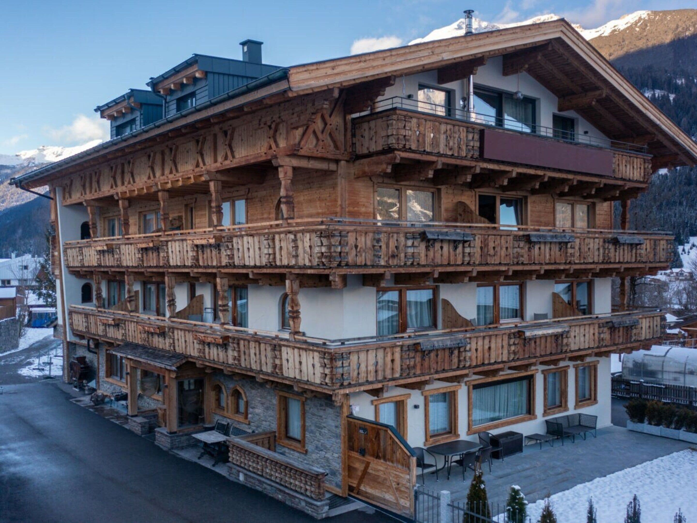Ein mehrstöckiges Holzgebäude mit Balkonen, großen Fenstern und einem Steinsockel.