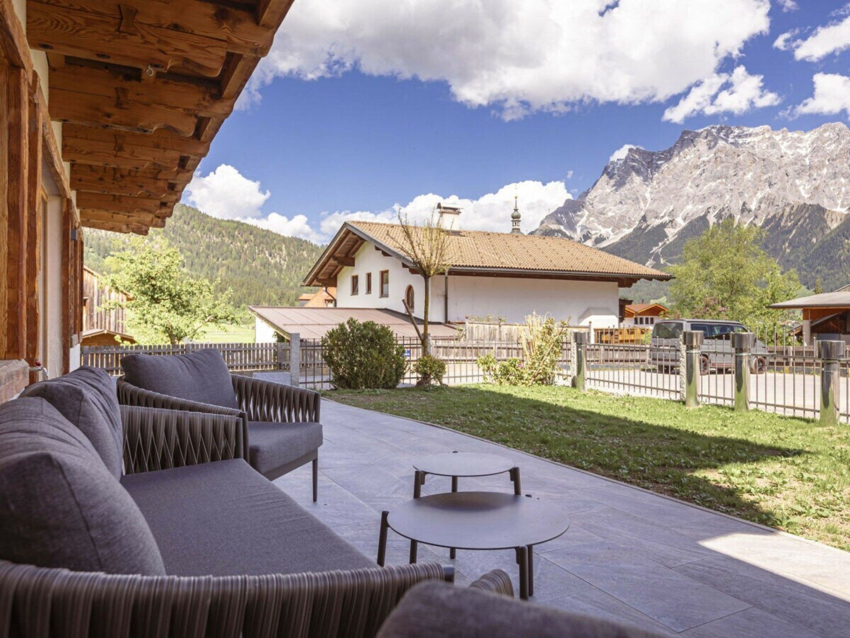 A covered outdoor seating area with a view of a mountain and a building.