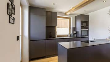 A modern kitchen with dark cabinetry, a central island, and built-in appliances.