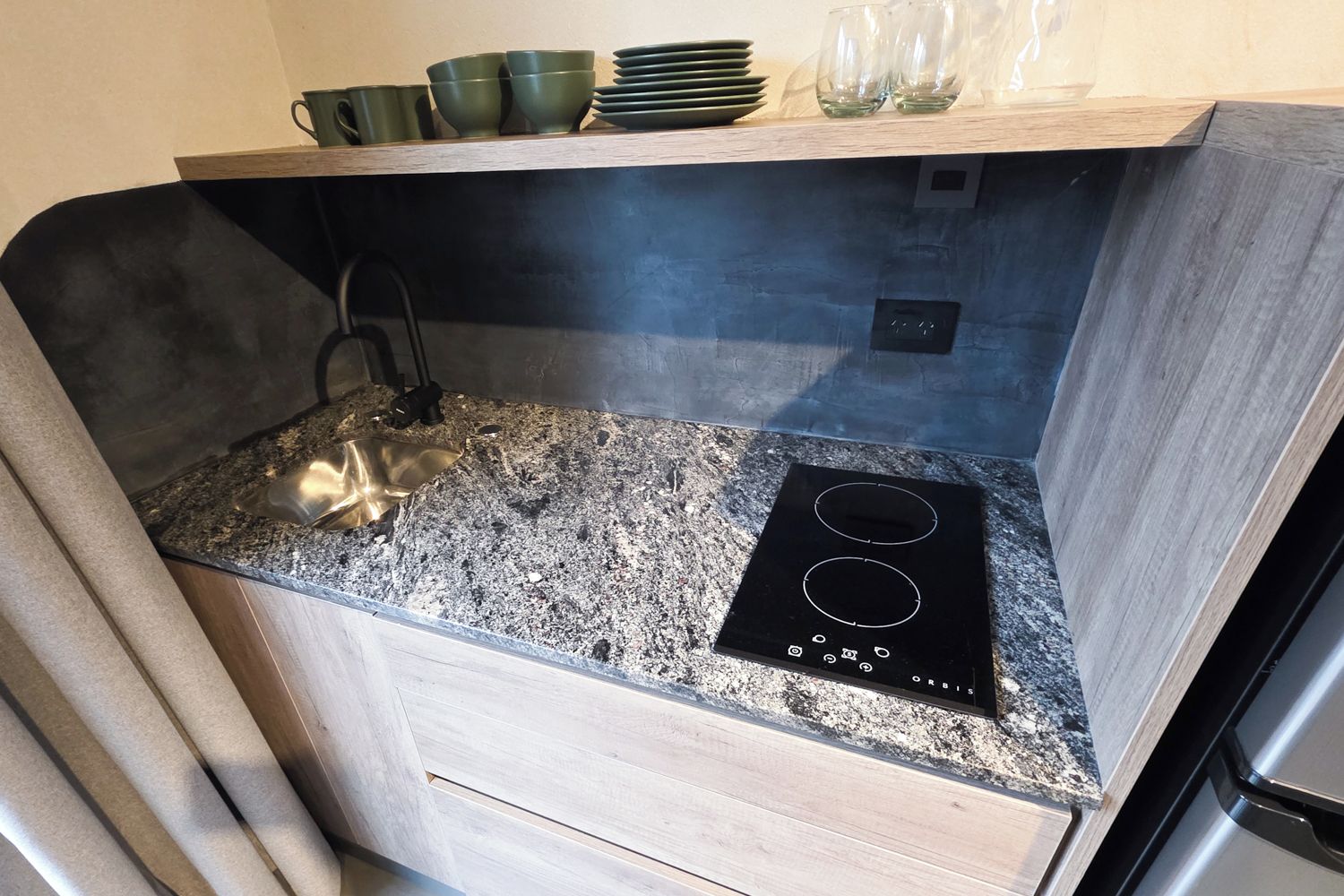 A compact kitchen with a built-in stove, a sink, and a wooden countertop.