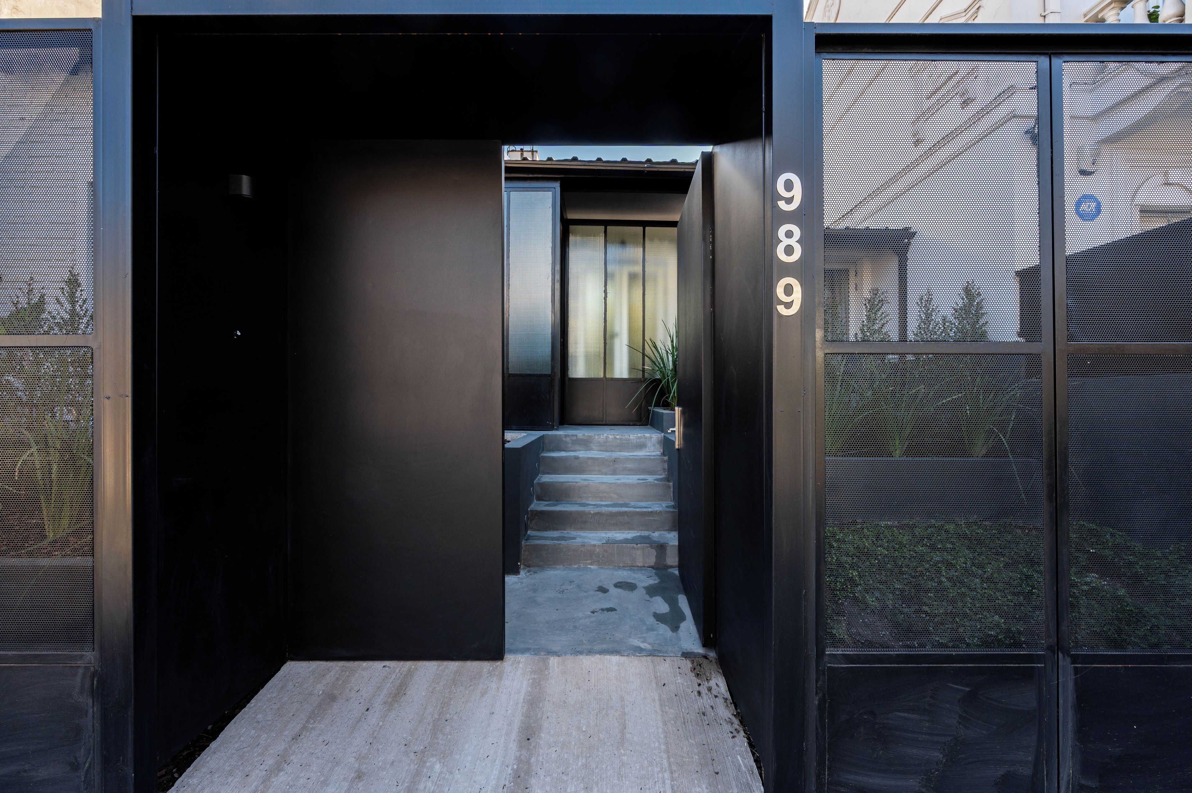 A modern building entrance with a concrete staircase leading to a door marked with the number 989.