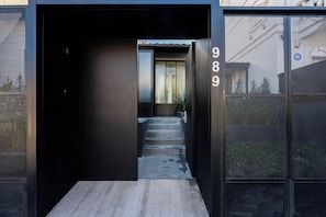 Una entrada moderna de edificio con una escalera de hormigón que conduce a una puerta marcada con el número 989.