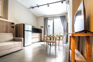A modern living room with a sofa, a dining table with chairs, a kitchen area, and a television on a stand. - MOT River Plate Lux Lofts (Buenos Aires)
