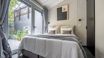 Un dormitorio con una cama grande, una puerta corrediza de vidrio a un balcón y un cuadro en la pared.