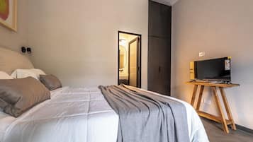 A hotel room with a bed, a television on a wooden stand, and a wardrobe.