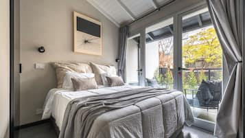 Un dormitorio con cama, ventana y vistas al exterior.