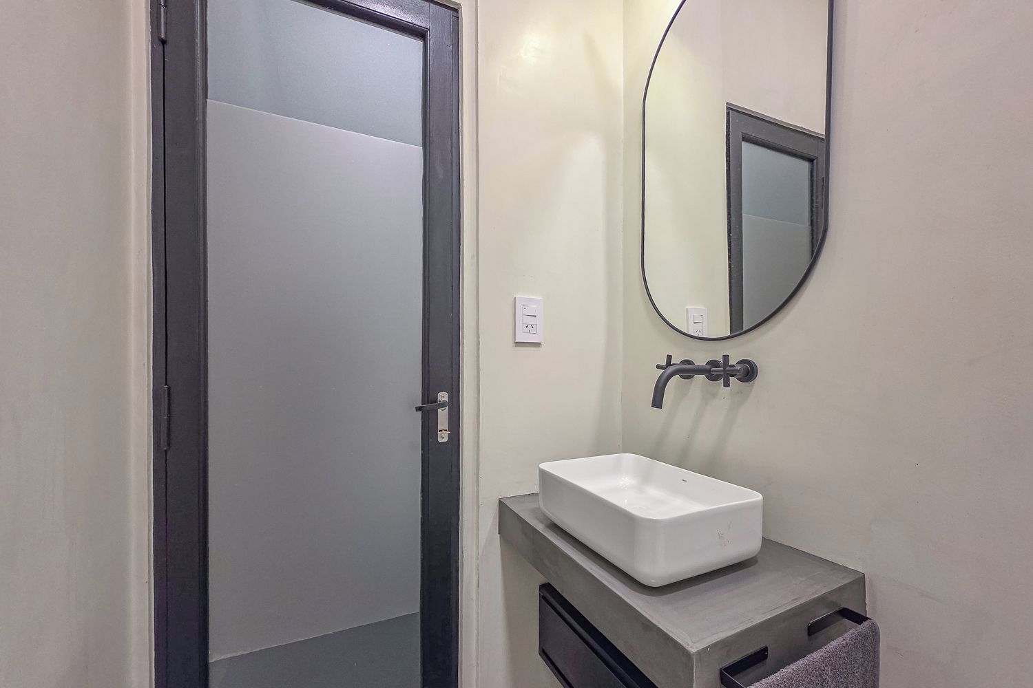 A bathroom with a white sink, a mirror, and a door.