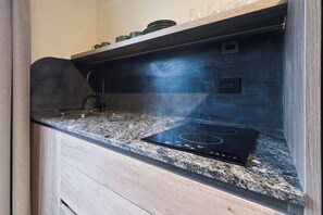 A kitchen with a built-in induction cooktop, a stainless steel range hood, and a granite countertop. - MOT River Plate Lux Lofts (Buenos Aires)