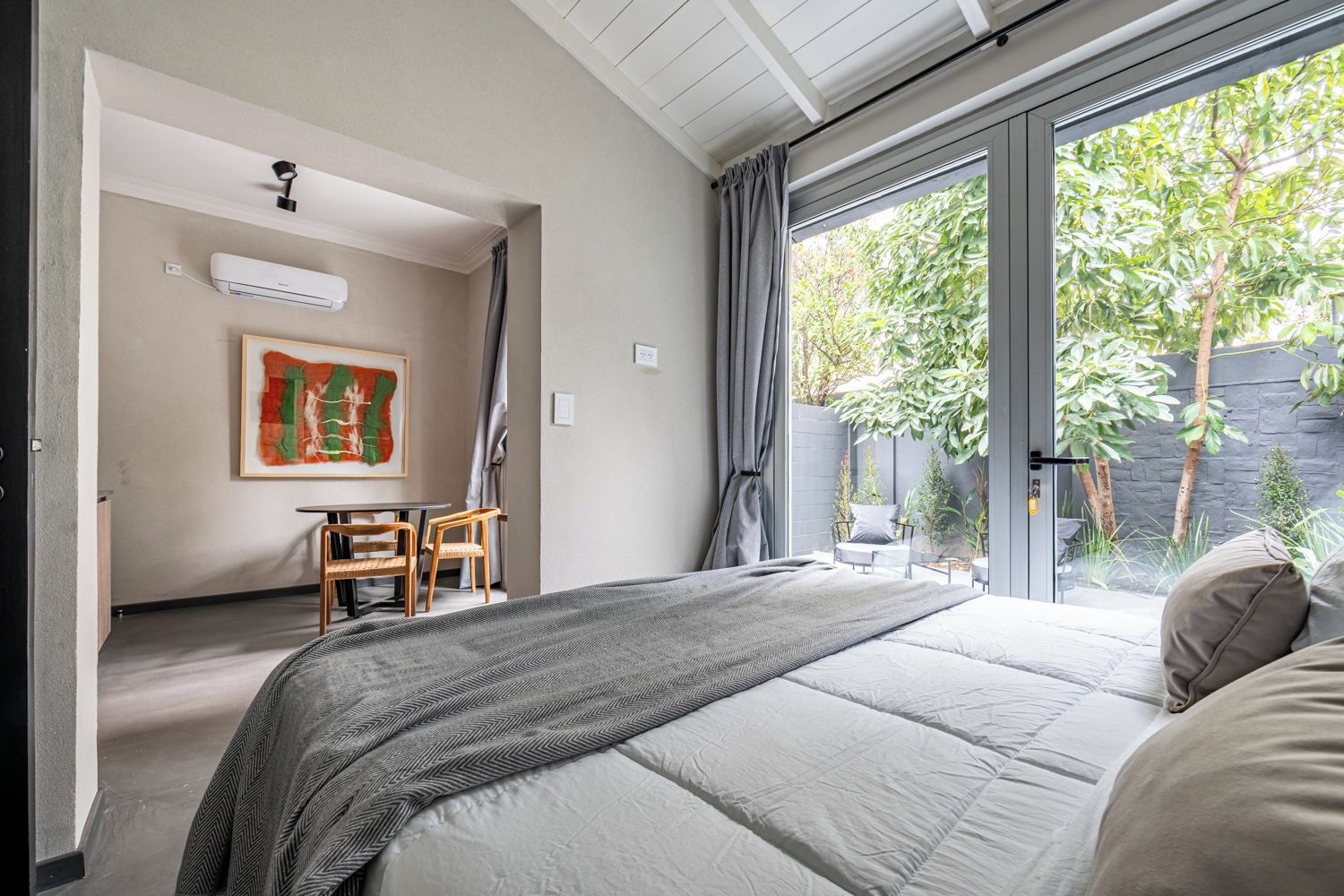 Un dormitorio con una cama grande, un escritorio, una silla, una ventana con cortinas y un cuadro en la pared.