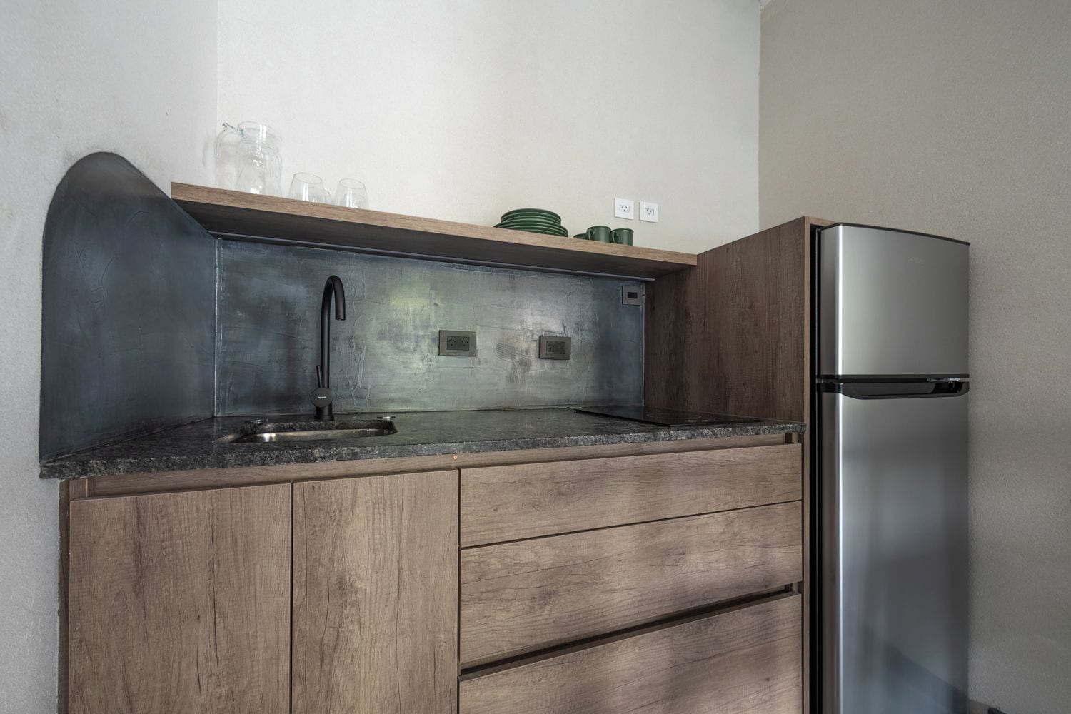 Une cuisine équipée d’un réfrigérateur en acier inoxydable, d’un évier avec un robinet moderne, de meubles de rangement en bois et d’un plan de travail.