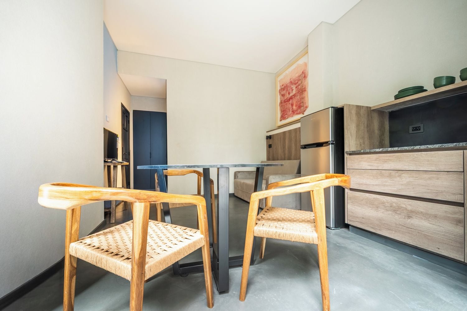 Una cocina compacta con dos sillas de madera, una mesa de comedor, un refrigerador y un armario de madera.