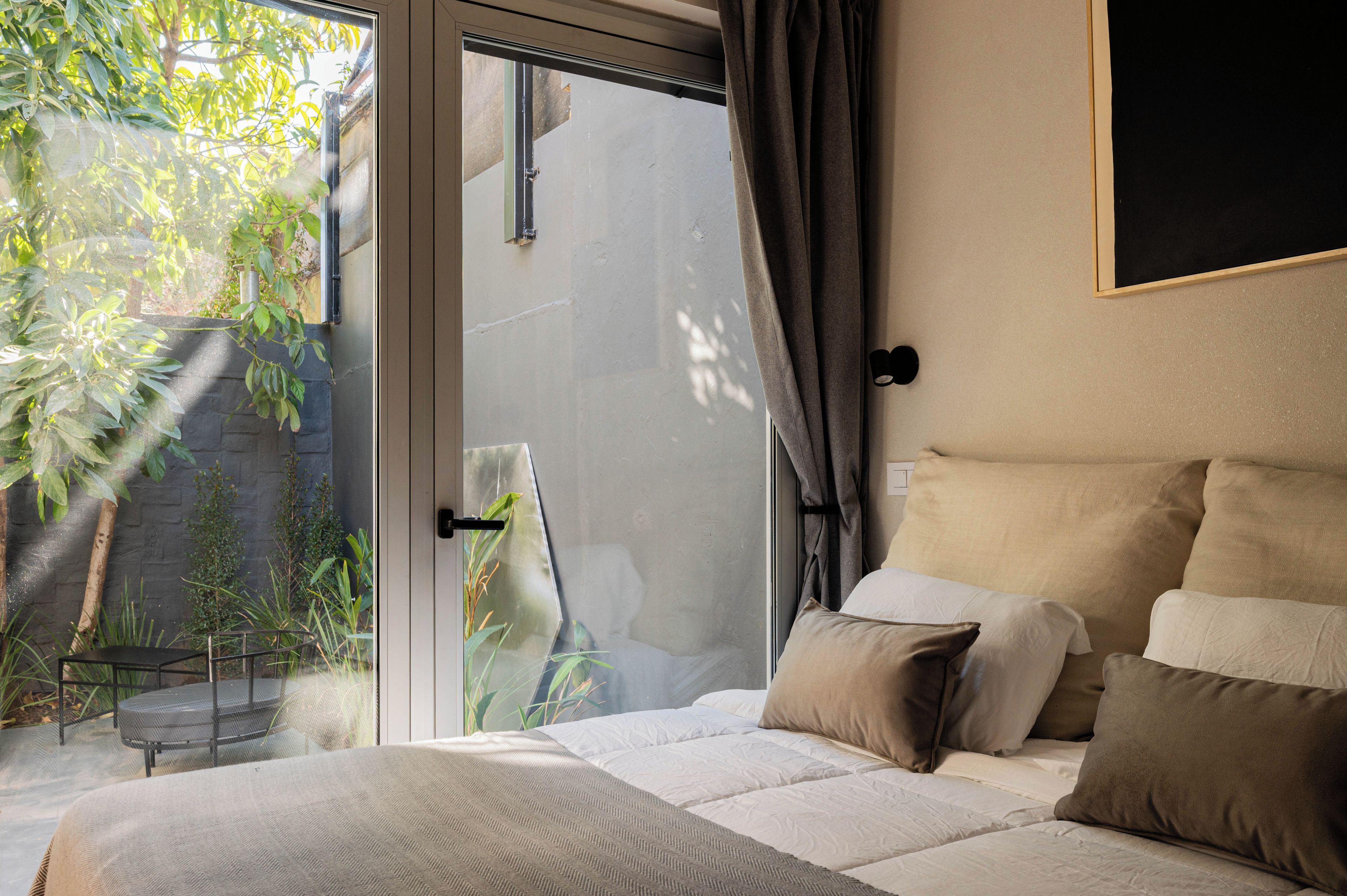 A bedroom with a bed, a window, and a view of greenery outside.