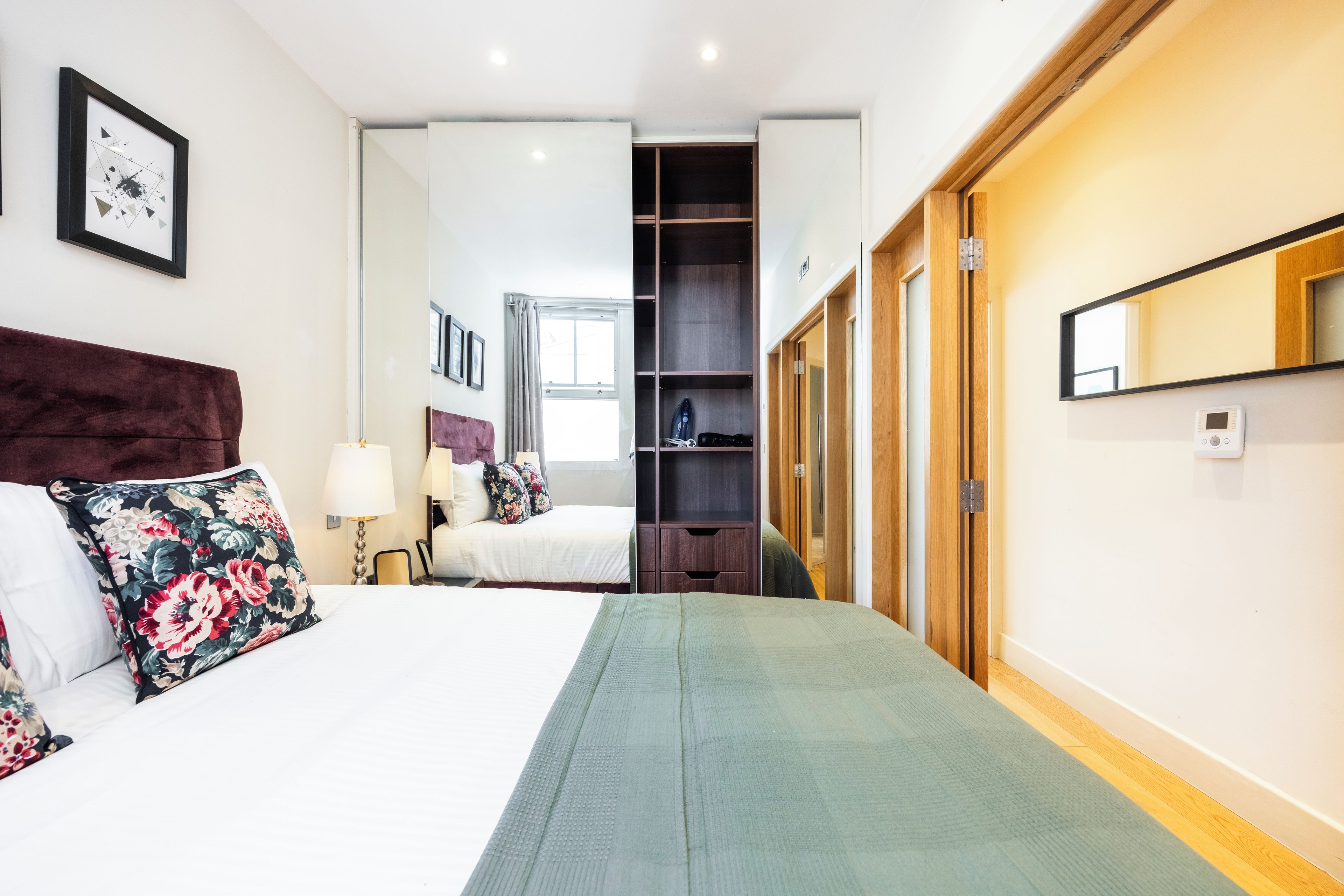 Una habitación de hotel con cama, armario, espejo y ventana.