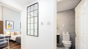 Una habitación de hotel con cama, mesita de noche y una obra de arte enmarcada en la pared.