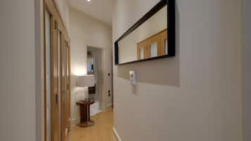 Un couloir doté d’un plancher en bois, d’un miroir au mur et d’une porte donnant sur une autre pièce.