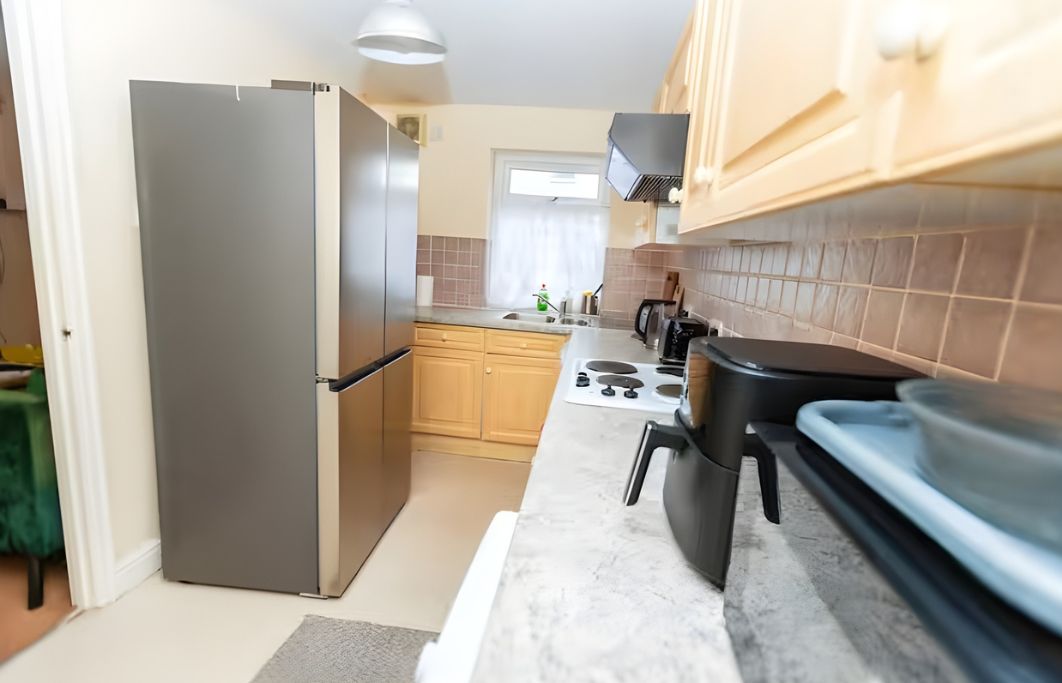 A kitchen with a refrigerator, stove, and wooden cabinets.