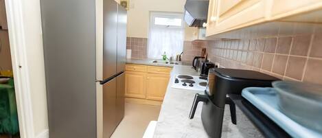 A kitchen with a refrigerator, stove, and wooden cabinets.