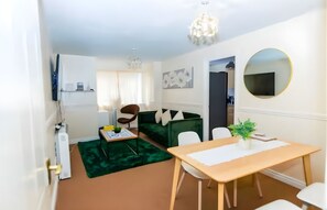 Un soggiorno moderno con un divano verde, un tavolo da pranzo in legno e un lampadario.