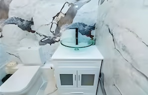 Un bagno con un lavandino bianco, uno specchio e un WC.
