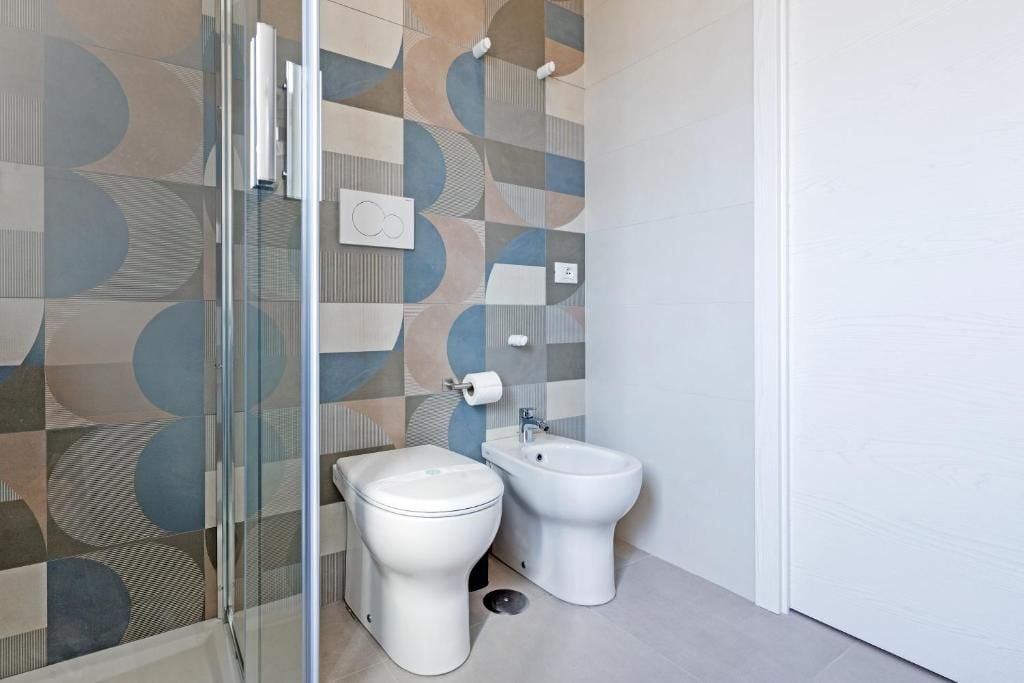 A bathroom with a toilet, bidet, and glass shower enclosure.