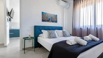 Una habitación de hotel moderna con un cabecero azul, un cuadro en la pared y vistas al exterior a través de cortinas translúcidas.