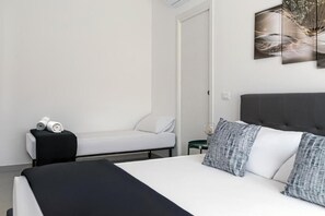Un dormitorio moderno con cama, mesita de noche, silla y una obra de arte colgada en la pared.