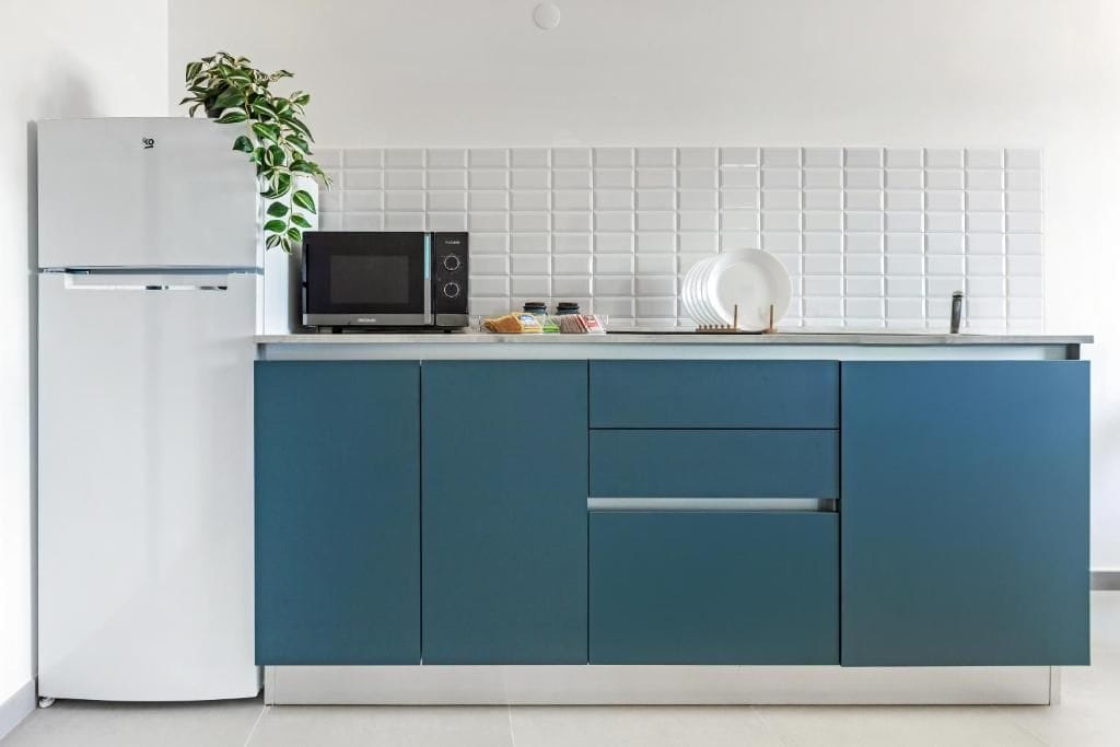 A kitchen with a white refrigerator, a microwave, and a blue cabinet.
