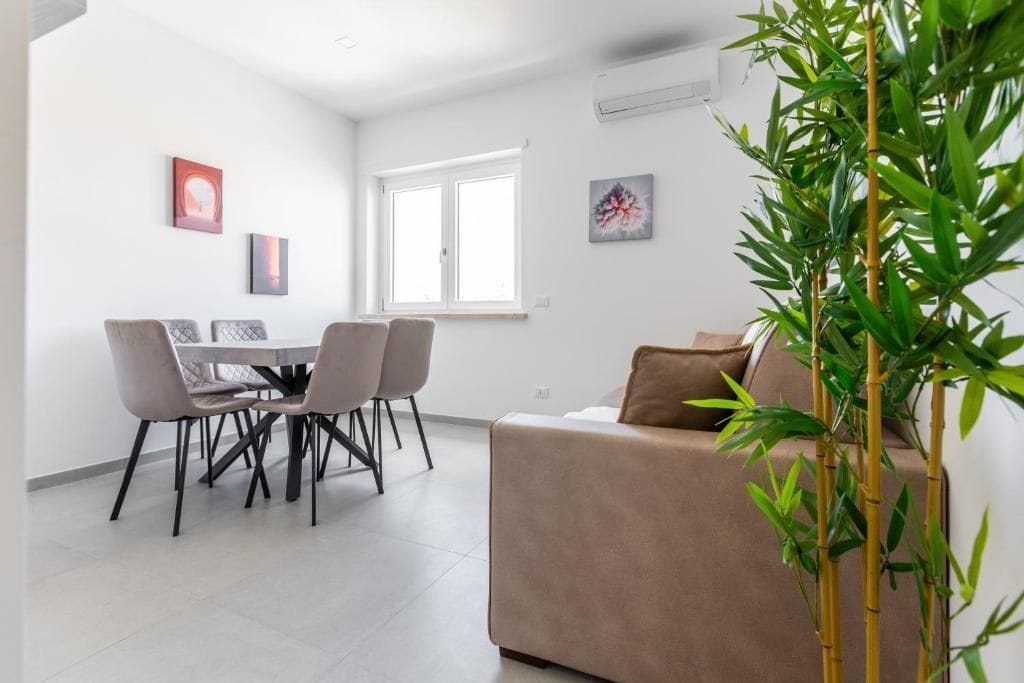 Un salon moderne avec un canapé, une table à manger et des chaises, ainsi qu’une grande fenêtre.