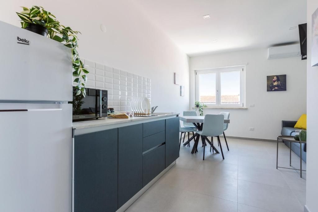 A modern kitchen with a refrigerator, a dining area with chairs and a table, and a window with a view.