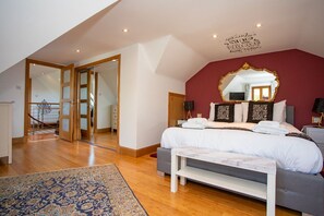 A bedroom with a large bed, a mirror, and a view of a staircase. - The Banking Hall -  a house  that sleeps 6 guests  in 2 bedrooms (Brightons)