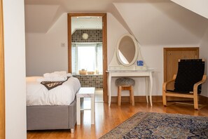 A bedroom with a bed, a desk, a chair, a mirror, and a view of the bathroom. - The Banking Hall -  a house  that sleeps 6 guests  in 2 bedrooms (Brightons)