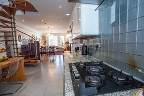 Une cuisine moderne dotée d’un îlot central, d’une cuisinière intégrée et d’un escalier menant à un niveau supérieur.