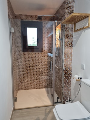 Un bagno con doccia, WC e finestra.