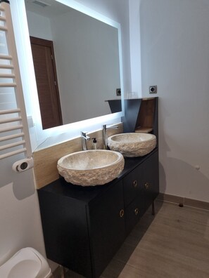 A bathroom with a double vanity, a large mirror, and a towel rack.