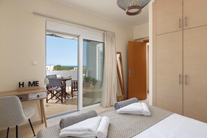 A bedroom with a bed, a desk, a chair, and a view of the outdoors through a sliding door. - Villa Olvia - Three Bedroom Villa, Sleeps 6 (Rhodes)
