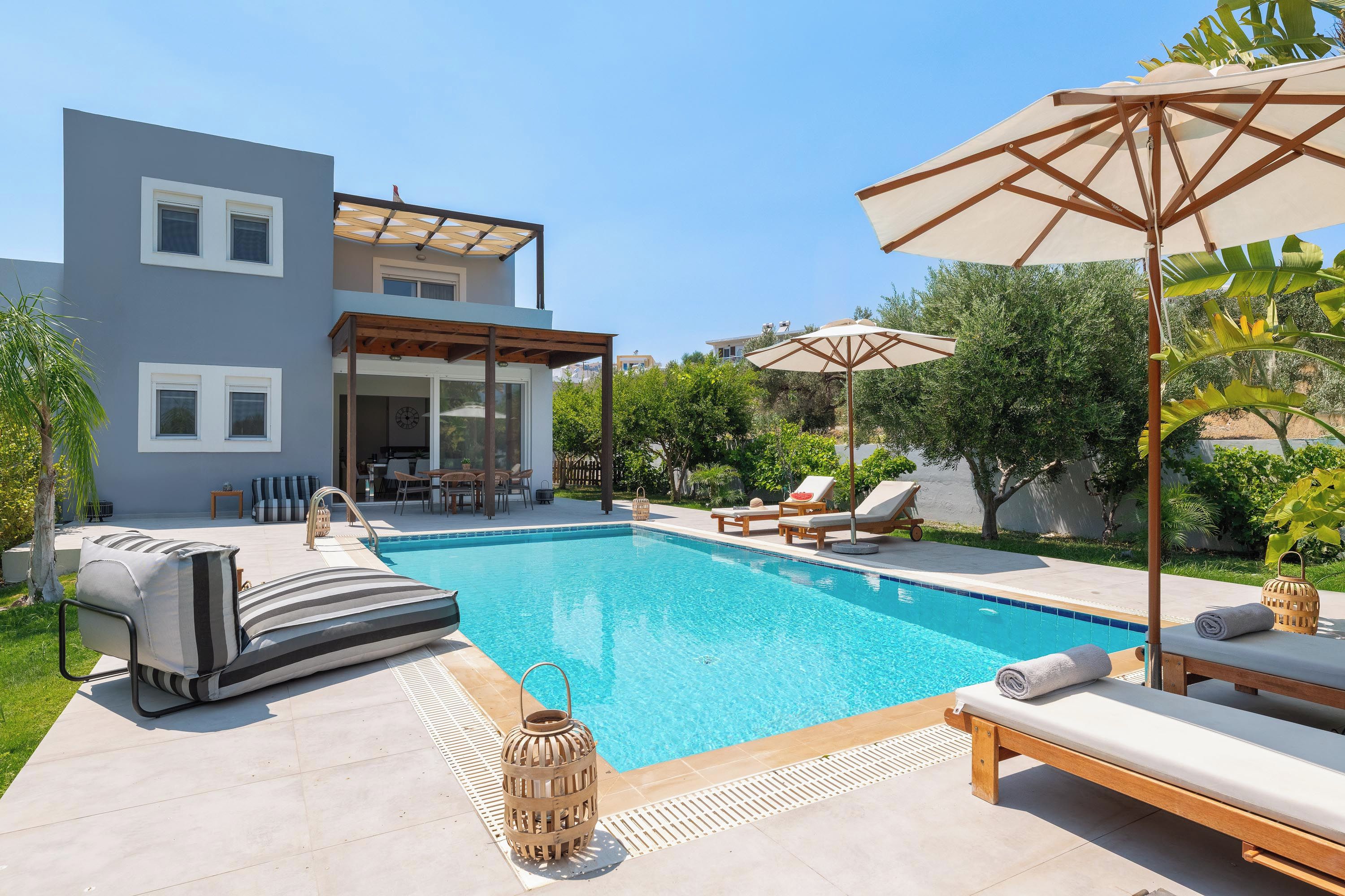 A modern pool area with a clear blue pool, lounge chairs, and a pergola.