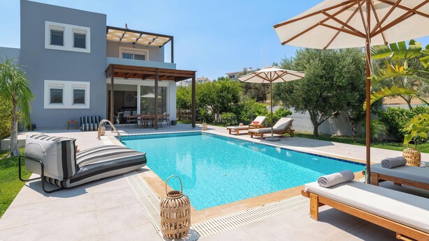 Un área de piscina moderna con una piscina azul cristalina, sillas de descanso y una pérgola.