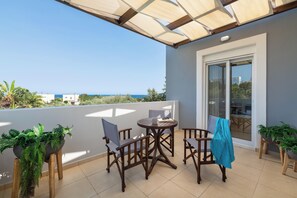 A balcony with a table and chairs, a potted plant, and a view of the sea. - Villa Olvia - Three Bedroom Villa, Sleeps 6 (Rhodes)