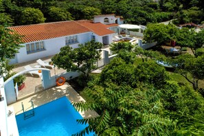 A large, white building with a red-tiled roof, surrounded by lush greenery and a swimming pool. - Villa Amelie - One Bedroom Villa, Sleeps 4 (Ixia)