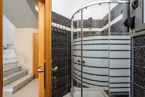 Un baño moderno con cabina de ducha de vidrio, una escalera de mármol y pared de baldosas blanco y negro.